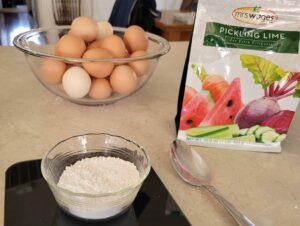 bowl of eggs with bag and dish of pickling lime on countertop