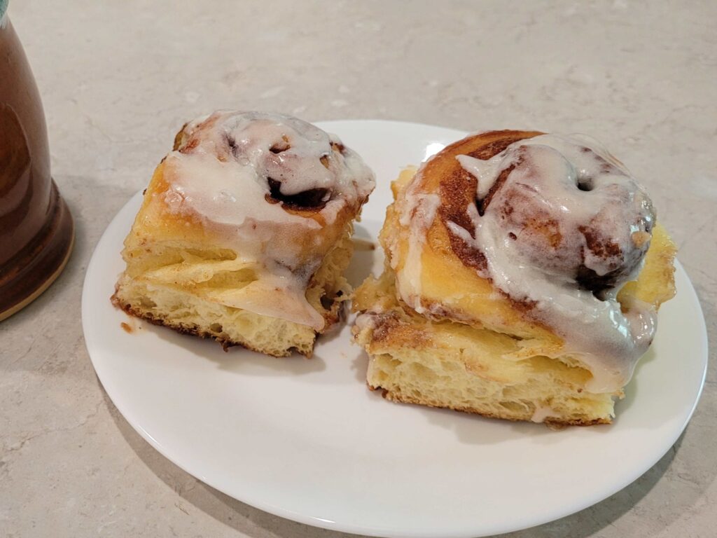 2 cinnamon rolls with frosting on a white plate