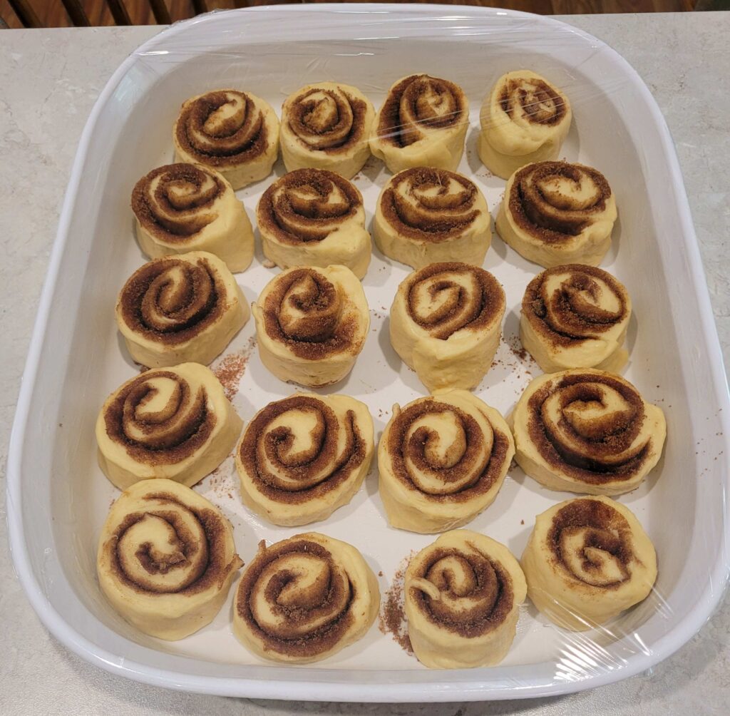 uncooked cinnamon rolls in a white casserole pan before rise 2