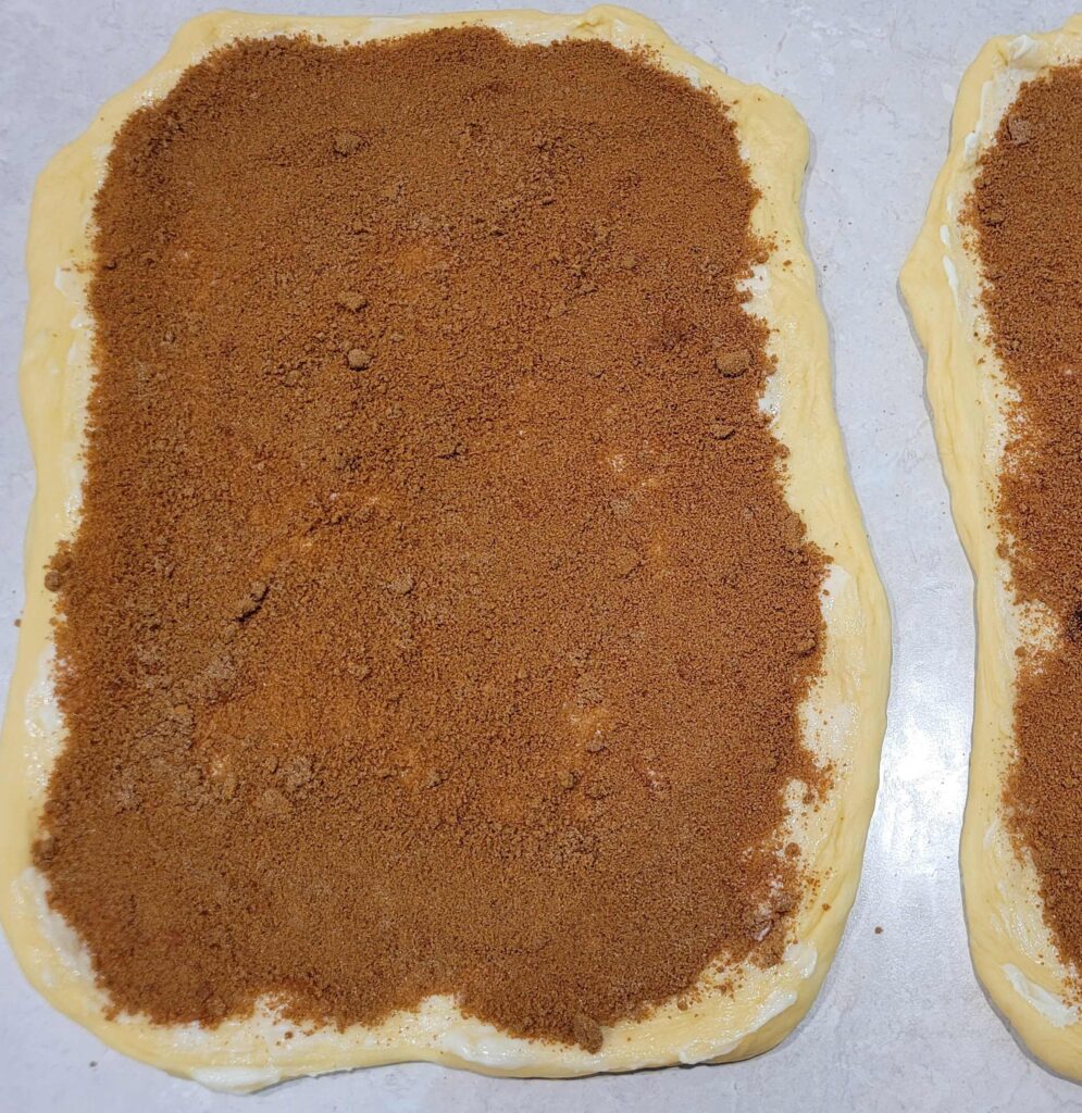 Cinnamon dough rolled out with cinnamon and sugar filling 